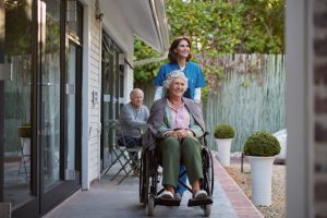 Nurse assisting senior woman in the park of a retirement home