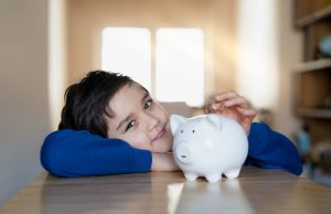 Schoolkid putting coins into piggy bank,Child boy counting saving money, Children learning financial